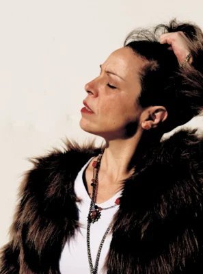 La chanteuse et musicienne Carine Lotta avec les yeux fermés, de profil, sur un fond blanc