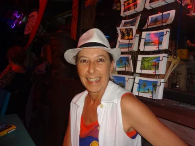 Une femme avec un chapeau blanc et un t-shirt sans anche pose pour un portrait photo en intérieur