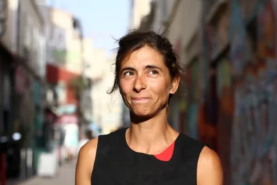 Sophie Laffont habillée en noir regarde hors-champ, derrière elle un fond urbain flou