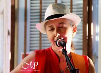 Une femme avec un chapeau blanc chante devant un micro