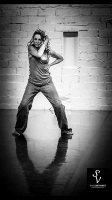 Portrait en noir et blanc de la danseuse et comédienne Fabienne Gounon, debout, dans une salle