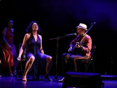 Deux femmes sur un scène bleue-violet en train de jouer et chanter