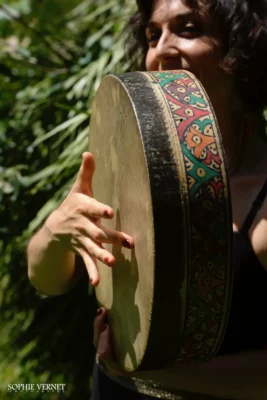 Un tambour en premier plan et en deuxième plan une femme en train de le jouer