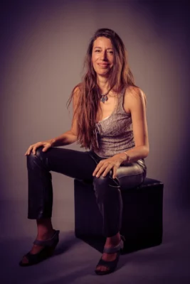 La comédienne Monika Smiechowska assise, derrière elle un fond noir éclairé