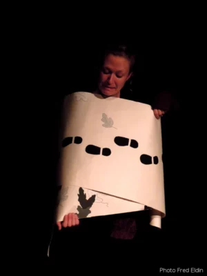 La marionnettiste Marion Lalauze enveloppé d'un rouleau en papier sur un fond noir