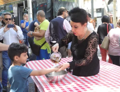 Une femme habillée en noir, élégante, nettoie les mains d'un enfant avec de l'eau