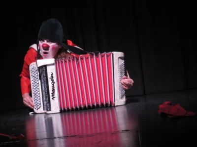 Véronique Martin, alias la clowne Lulu, allongée sur le sol, cachée à moitié derrière un accordéon