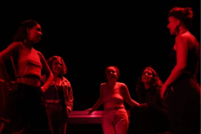Photo du spectacle Des Créatures : sous une lumière rouge des femmes discutent en cercle