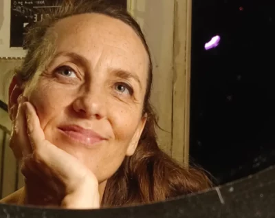 Gros plan d'une femme souriante, la main sur le menton et le regard hors-caméra