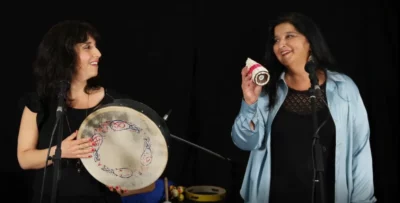 Deux femmes, une avec un tambour en main, l'autre avec une petite percussion