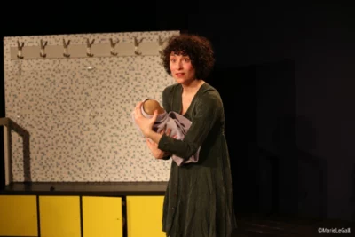 Une femme sur une scène de théâtre tient dans les bras une poupée