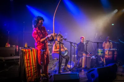 Quatre femmes sur scène avec différents instruments musicaux sur un fond de lumières bleues