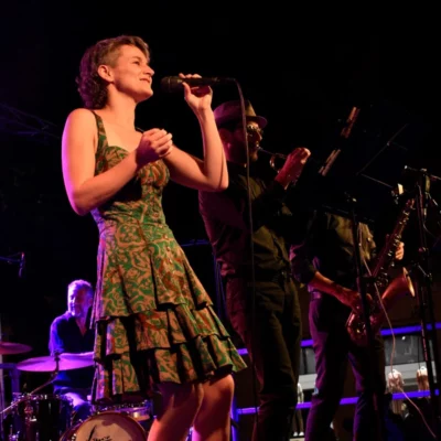 La chanteuse et compositrice Maud Revol lors d'un concert avec un groupe sur scène avec elle