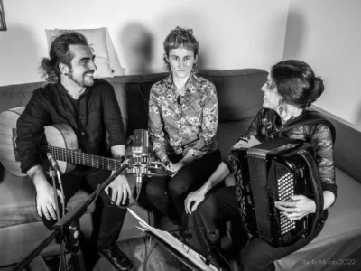 Le Maud Revol Trio dans un salon, assis sur un canapé avec les instruments et les micros