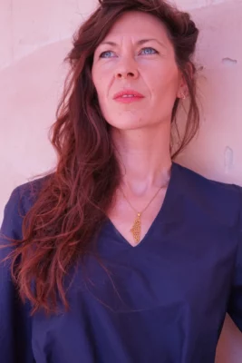 Photo en couleur sur un fond blanc d'une femme avec une chemise bleu qui regarde vers le haut en diagonal