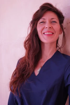 Une femme souriante avec les cheveux détachés et une chemise bleu