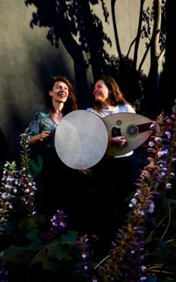 Photo en couleurs de deux femmes en extérieur avec des instruments musicaux en main