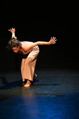 Juliana Mejia, interprète et chorégraphe, danse sur une scène de théâtre dans un fond noir