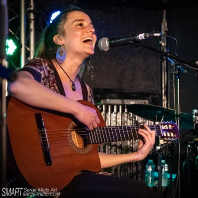 Jeune femme en train de chanter et jouer la guitare lors d'un concert