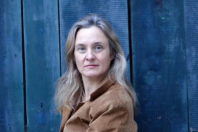 La conteuse et danseuse Gisèle Isnardon pose pour un portrait en plan poitrine sur un fond bleu
