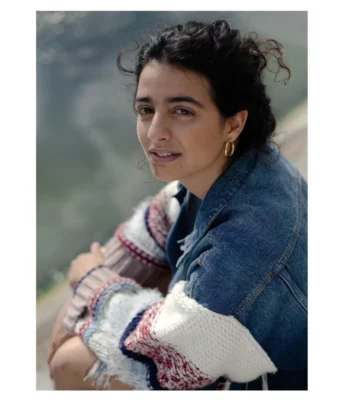 Lior Aidan, comédienne et metteure en scène, assise, en extérieur, sur un fond flou