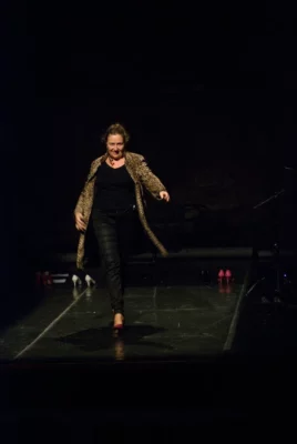 Cécile Etcheto, comédienne et metteure en scène, marche sur un plateau vide avec un fon noir