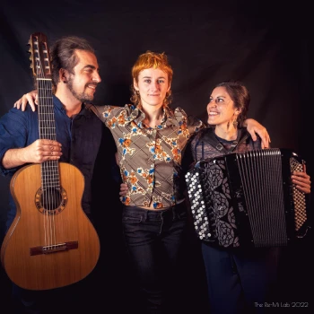 Photo de groupe: un homme avec une guitare, une femme au milieu, une autre femme avec un accordéon