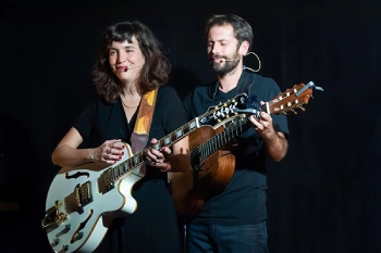 Une femme et un homme sur fond noir en train de jouer des instruments à cordes