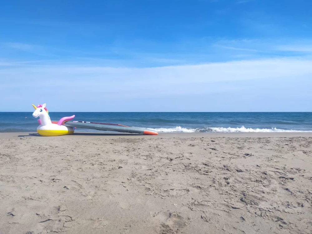 Paysage marin avec du sable blanc, un hippocampe en plastique sur la gauche et la mer sur le fond