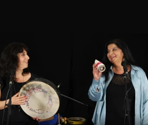 Deux femmes sur un fond noir avec des instruments musicaux à la main, en train de jouer