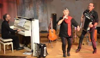Deux hommes avec des instruments musicaux et une femme en train de chanter sur une scène de concert