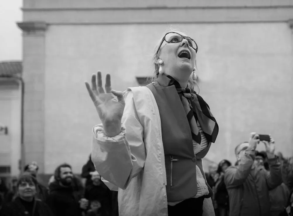 Photo en noir et blanc de la clowne Mélissa Streicher en extérieur avec du public