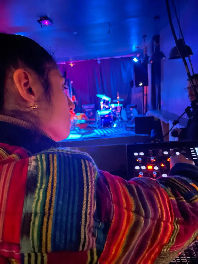 Une jeune femme de dos en train de travailler sur une console pour un concert