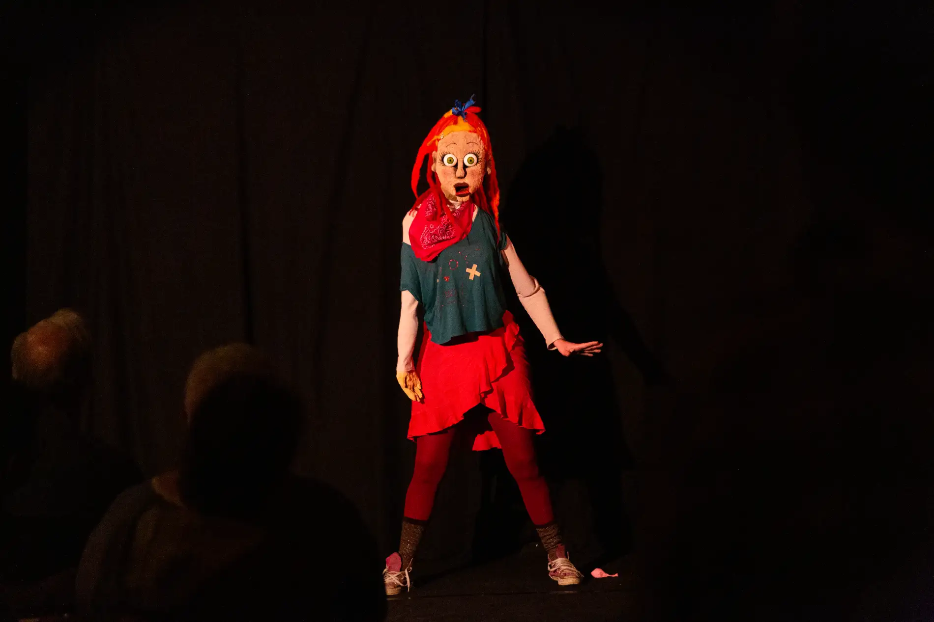 Une femme sur scène devant un public, déguisée en marionnette