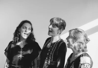 Photo en noir et blanc en intérieur de trois femmes en train de chanter
