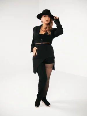 Jeune femme habillée en noir sur fond blanc avec un chapeau