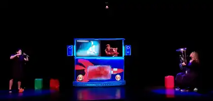 Trois personnes sur une scène de théâtre au fond noir en train de jouer