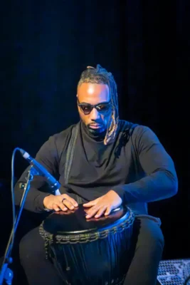 Un homme assis, assis, en train de jouer des percussions devant un micro