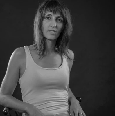Photo en noir et blanc d'une femme en débardeur blanc assise