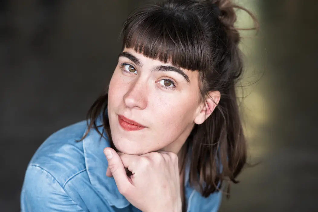 Photo d'une jeune femme qui regarde l'appareil photo avec une main posée sous le menton
