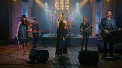 Quatre femmes et deux hommes en train de jouer des instrument sur une scène musicale