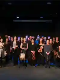 Un groupe de personnes, femmes et hommes, avec des instruments à la main sur un scène de spectacle