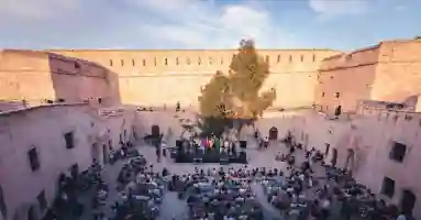 Photo de la cour d'un château dans laquelle un public assis assiste à un concert