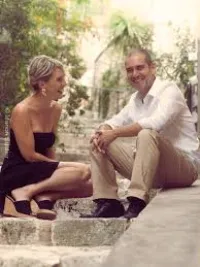 Un homme et une femme, assis sur des gradins, en extérieur, sourient