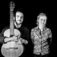 Un homme avec une guitare et une femme l'un à côté de l'autre dans une photo en noir et blanc